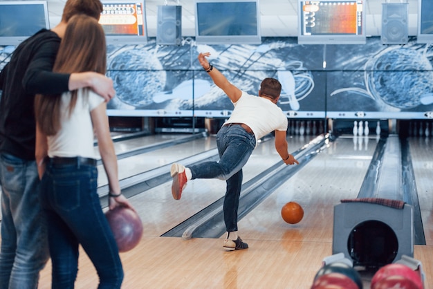 Hágalo con fuerza ligera. Jóvenes amigos alegres se divierten en el club de bolos en sus fines de semana