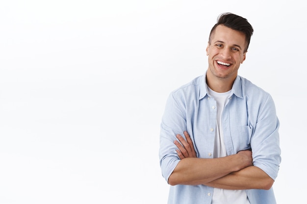 Hagamos negocios directos. Retrato de joven riendo despreocupado y relajado, con los brazos cruzados sobre el pecho en actitud preparada y profesional, entusiasta, administrando su propia pequeña tienda, pared blanca