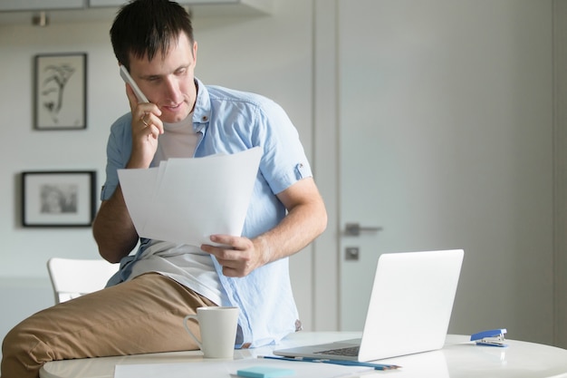 Half-length retrato del hombre, sentado en el escritorio con el teléfono