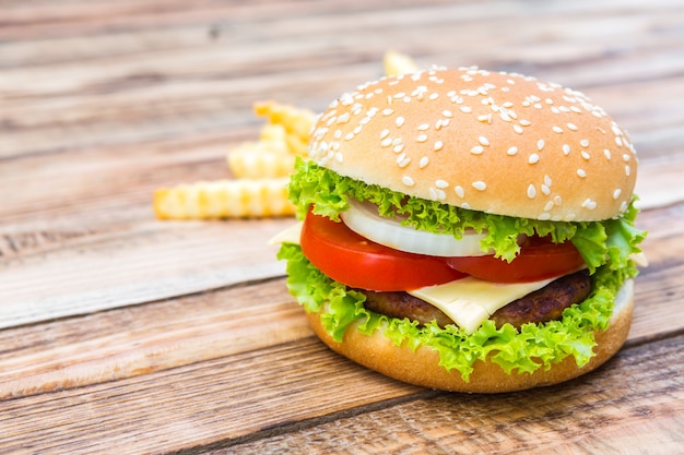 Hamburguesa apetitosa con patatas fritas de fondo