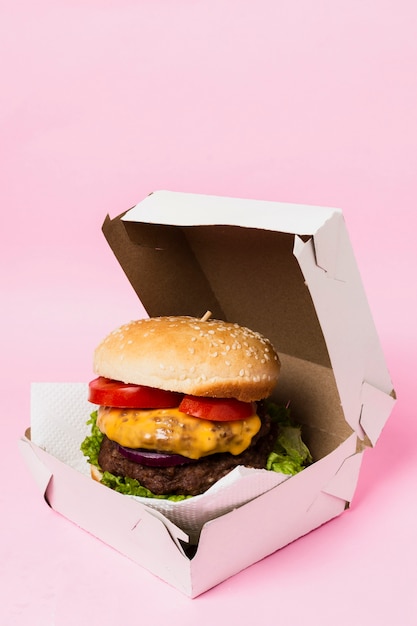 Hamburguesa en caja blanca sobre fondo rosa