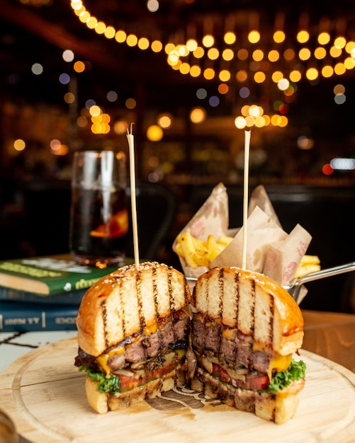 Foto gratuita hamburguesa de carne en bollo de pan cortado en dos trozos.