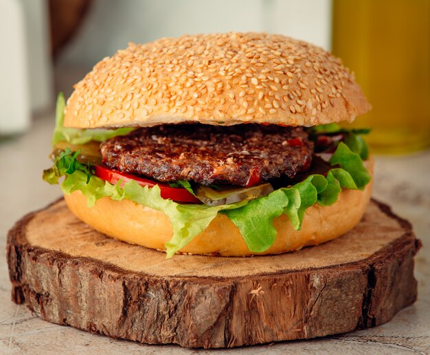 hamburguesa de carne grande en tablero de madera