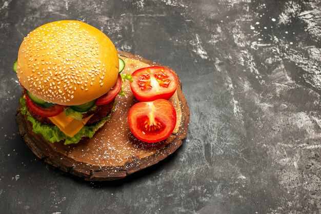 Hamburguesa de carne de media vista superior con verduras en el sándwich de comida rápida de bollo de superficie oscura