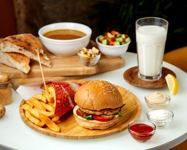 Hamburguesa de carne con papas fritas y un vaso de ayran