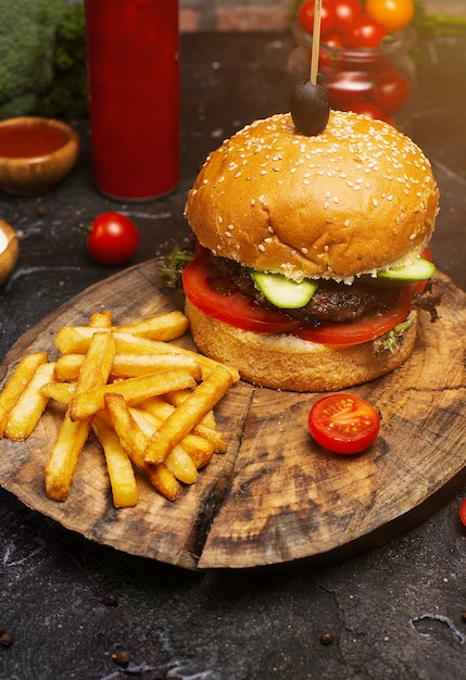 Hamburguesa de carne sabrosa fresca y papas fritas en mesa de madera, ketchuo, tomates, vegetales