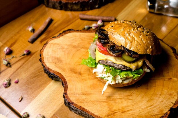 Hamburguesa de carne sobre tabla de madera ensalada de col pepino tomate champiñones queso vista lateral