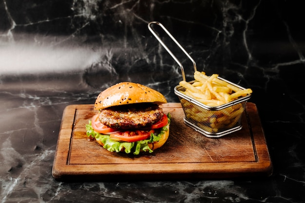 Hamburguesa con carne, tomate y lechuga servida con papas fritas.