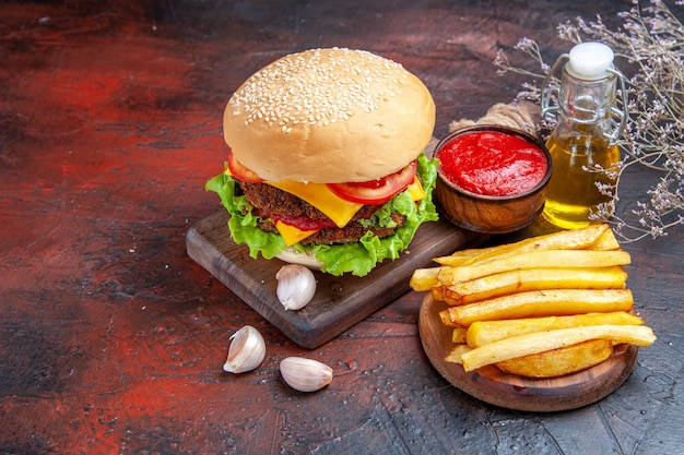 Hamburguesa de carne vista frontal con ensalada de queso y tomates en el fondo oscuro