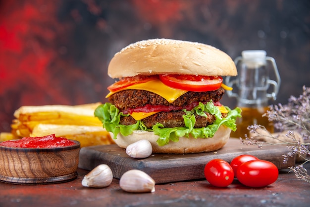 Hamburguesa de carne vista frontal con ensalada de queso y tomates en el fondo oscuro