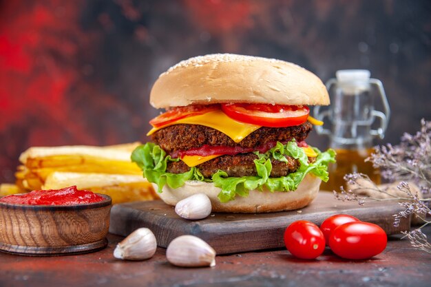 Hamburguesa de carne vista frontal con ensalada de queso y tomates en el fondo oscuro