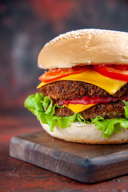 Hamburguesa de carne vista frontal con ensalada de queso y tomates en el fondo oscuro