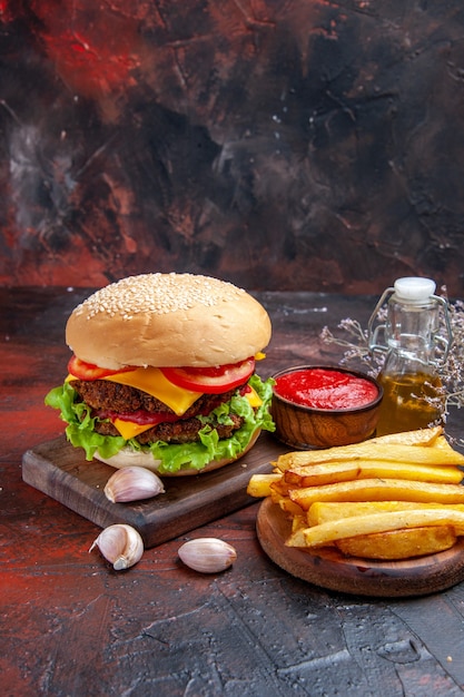 Hamburguesa de carne vista frontal con ensalada de queso y tomates en el fondo oscuro