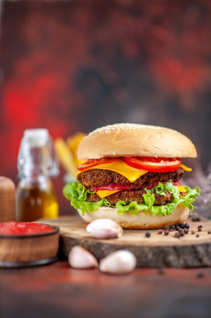 Hamburguesa de carne vista frontal con papas fritas en el fondo oscuro