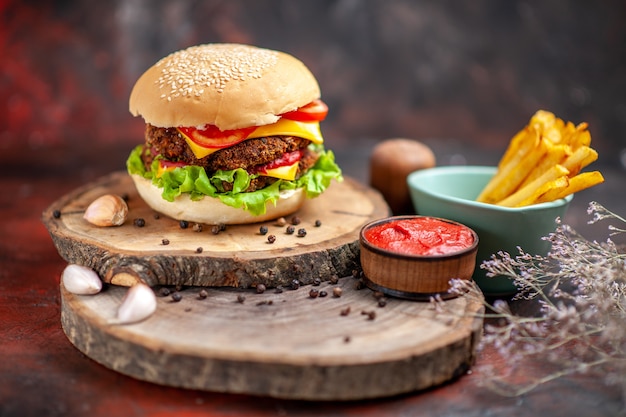 Hamburguesa de carne vista frontal con papas fritas en el fondo oscuro