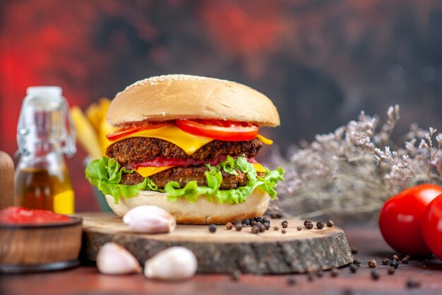 Hamburguesa de carne vista frontal con papas fritas en el fondo oscuro