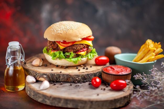 Hamburguesa de carne vista frontal con papas fritas en el fondo oscuro