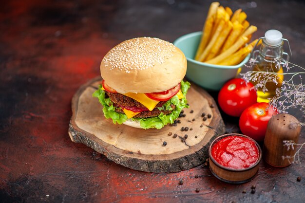 Hamburguesa de carne vista frontal con papas fritas en el fondo oscuro