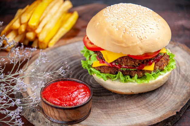 Hamburguesa de carne de vista frontal con queso, tomates y ensalada en el escritorio oscuro