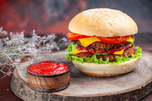 Hamburguesa de carne de vista frontal con queso, tomates y ensalada en el piso oscuro