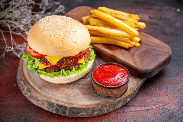 Hamburguesa de carne vista frontal con queso, tomates y ensalada sobre fondo oscuro