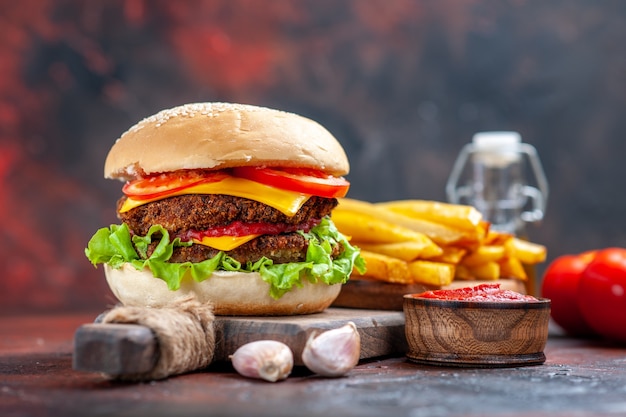 Hamburguesa de carne de vista frontal con tomate, queso y ensalada en el piso oscuro sándwich de pan de comida rápida