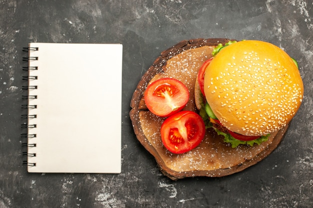 Hamburguesa de carne de vista superior con verduras en sándwich de comida rápida de bollo de superficie oscura