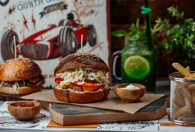 Hamburguesa con filete de ternera y ensalada dentro servida con una jarra de mojito