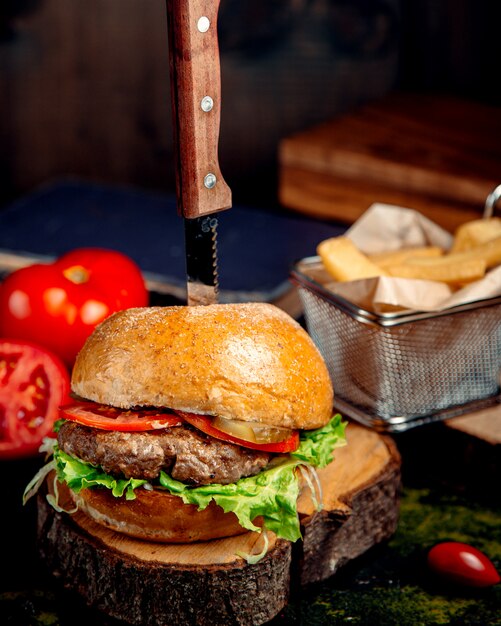 Hamburguesa fresca sobre tabla de madera