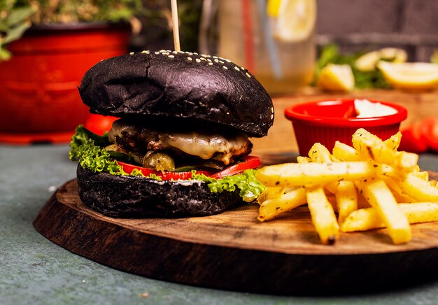Hamburguesa negra de chocolate con queso, carne, hamburguesa con verduras, comida rápida, papas fritas y salsa de tomate.