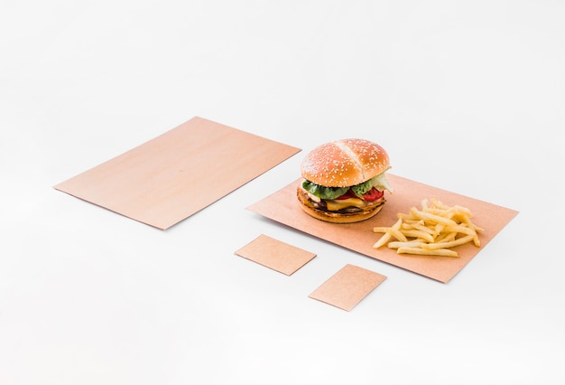 Hamburguesa y papas fritas en papel marrón sobre fondo blanco