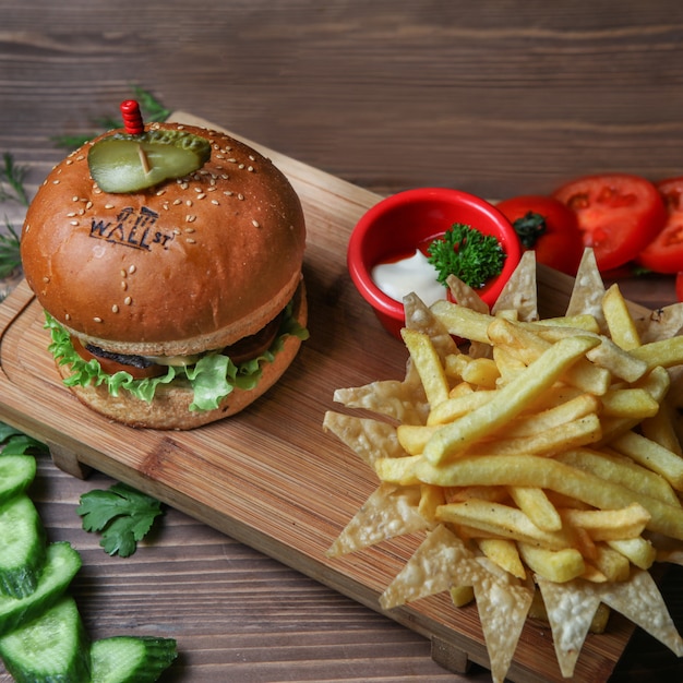 Hamburguesa con papas fritas, pepino, tomate y salsa.