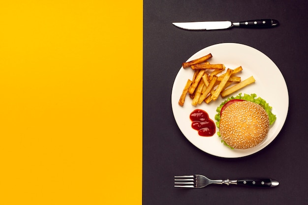 Hamburguesa y papas fritas en placa con espacio de copia