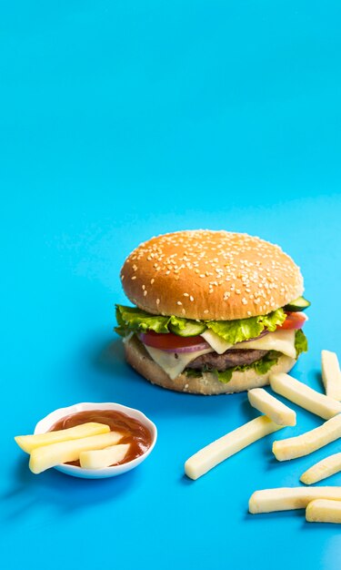 Hamburguesa y papas fritas sobre fondo azul.