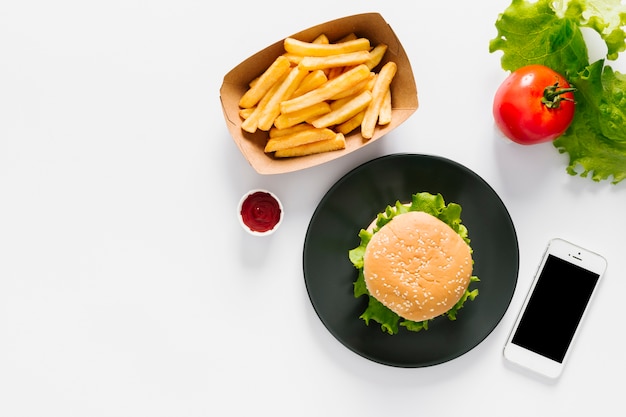 Hamburguesa plana y papas fritas en un plato con copyspace