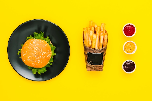 Foto gratuita hamburguesa plana con papas fritas y salsas.