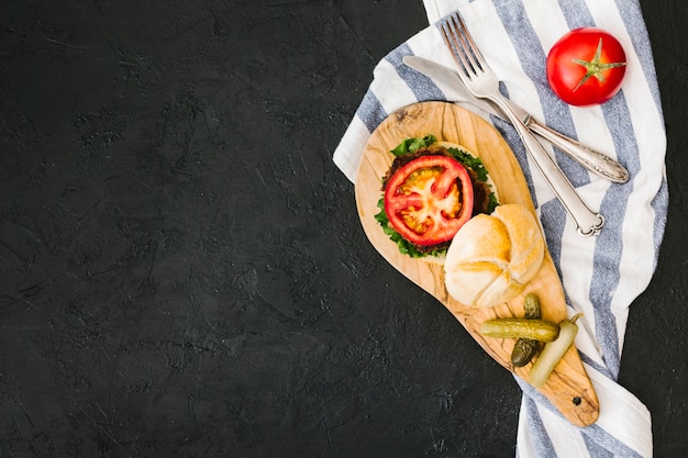 Hamburguesa plana y papas fritas sobre tabla de madera con copyspace