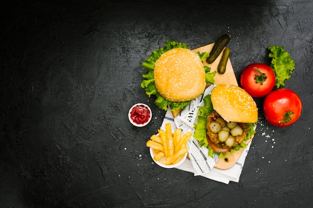 Hamburguesa plana y papas fritas sobre tabla de madera con copyspace