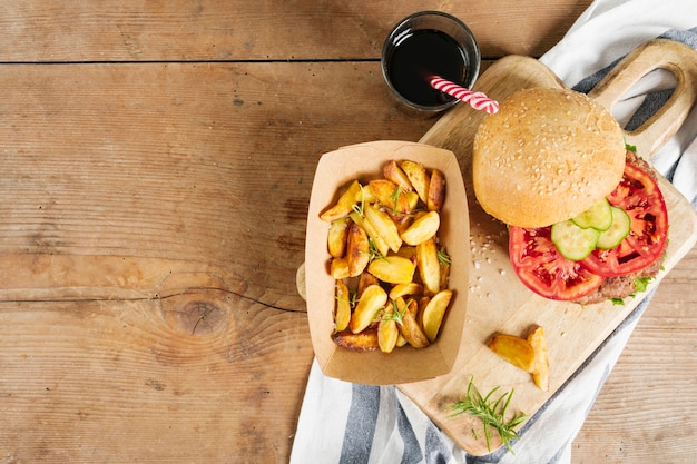 Hamburguesa plana y papas fritas sobre tabla de madera