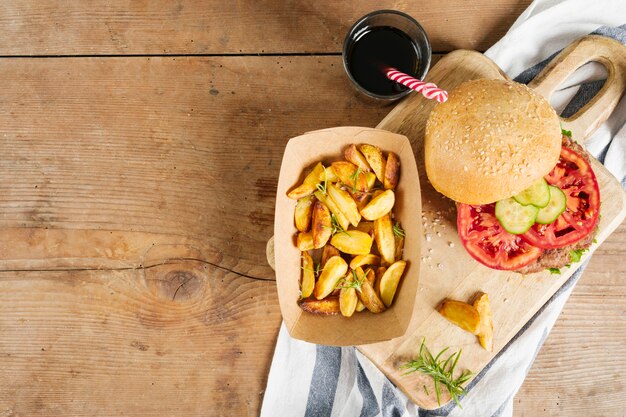 Hamburguesa plana y papas fritas sobre tabla de madera