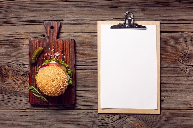 Foto gratuita hamburguesa plana con portapapeles maqueta