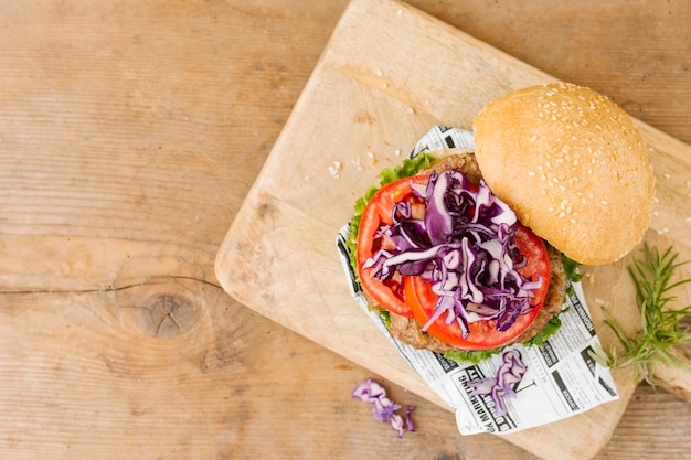 Foto gratuita hamburguesa plana sobre tabla de madera.