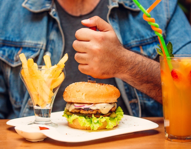 Hamburguesa de pollo con cebolla roja, queso derretido, pepino en vinagre, lechuga, tomate