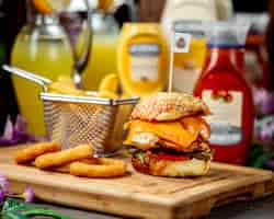 Foto gratuita hamburguesa de pollo con queso cheddar servido con papas fritas y salsa