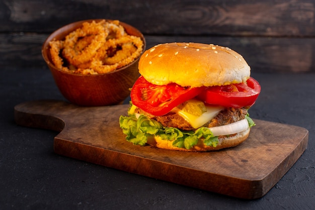 Una hamburguesa de pollo vista frontal con queso y ensalada verde en el escritorio de madera y comida rápida de sándwich