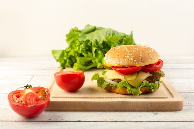 Una hamburguesa de pollo vista frontal con queso y ensalada verde en el escritorio de madera y comida rápida de sándwich