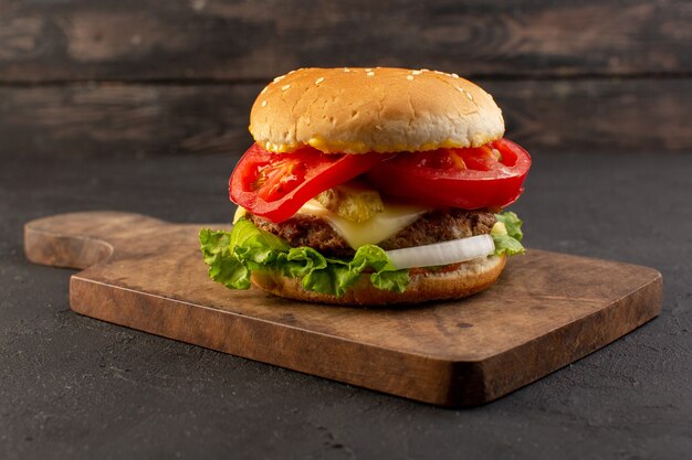 Una hamburguesa de pollo vista frontal con queso y ensalada verde en el escritorio de madera y superficie gris