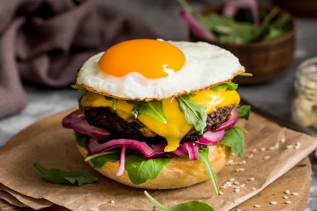 Hamburguesa con queso de alto ángulo con huevo frito en la tabla de cortar