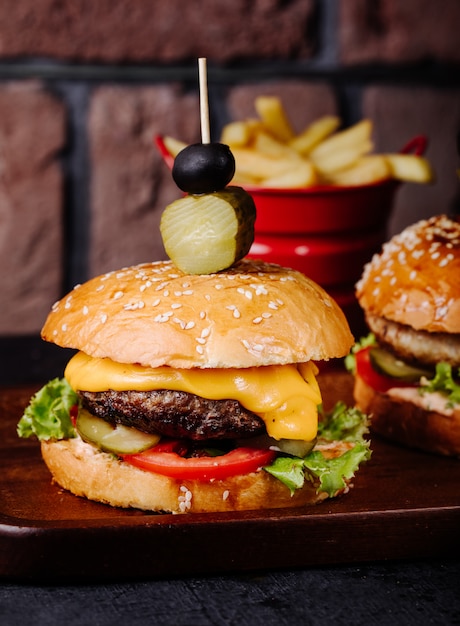 Hamburguesa con queso en bollo de pan con aceitunas en la parte superior.