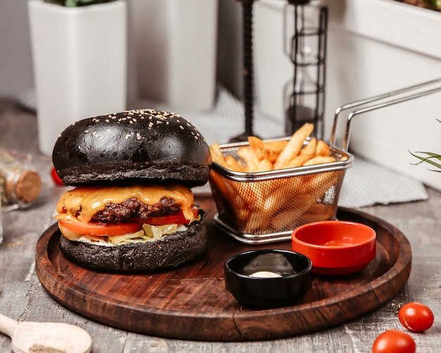 Hamburguesa con queso con pan negro y papas fritas